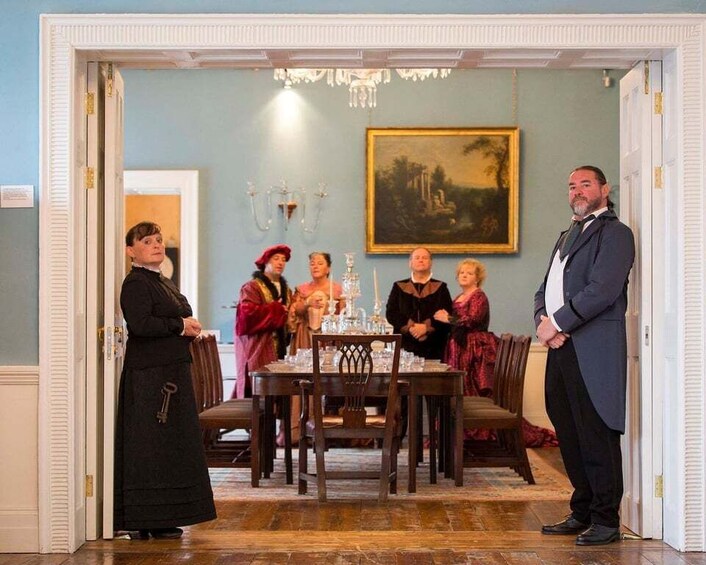 A formal dining room with a table set for a meal, a chandelier, and a painting on the wall. 2