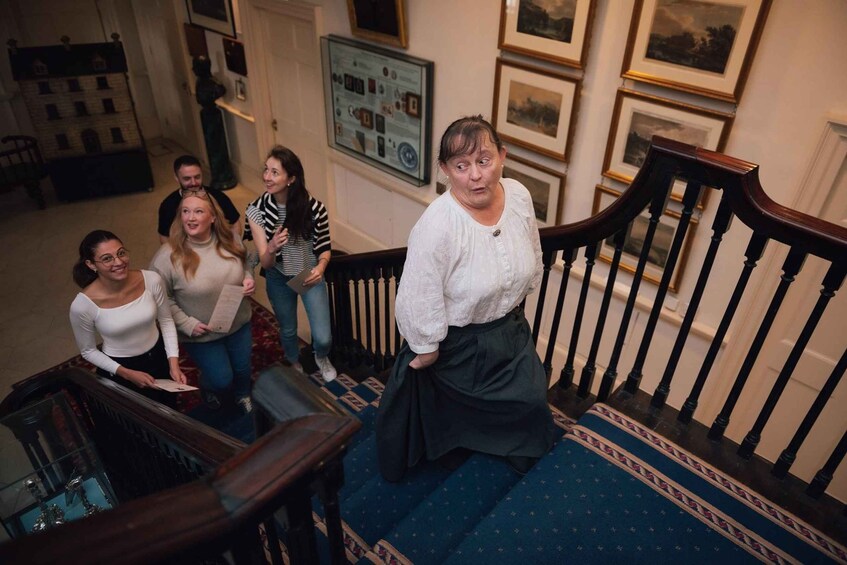 A group of people on a staircase with a blue carpet and wooden railing. 4