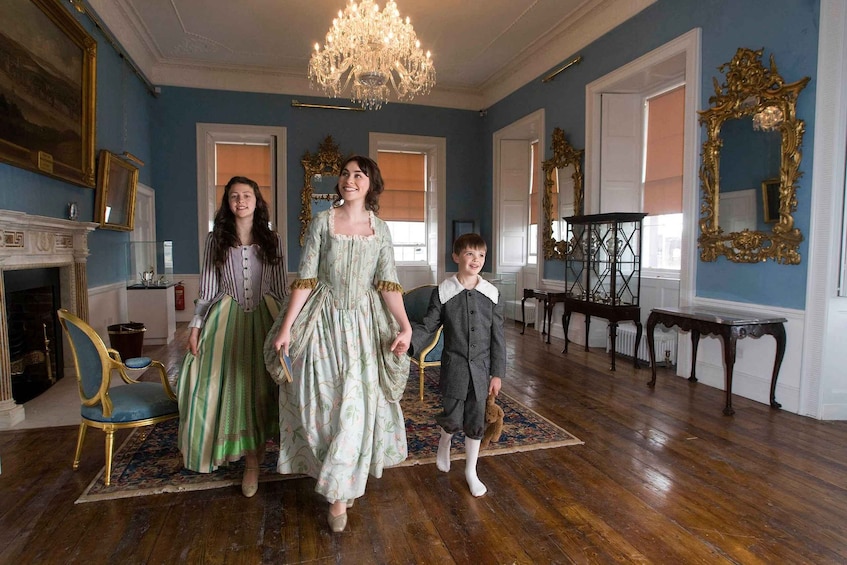 A room with blue walls, a chandelier, and ornate mirrors. 1