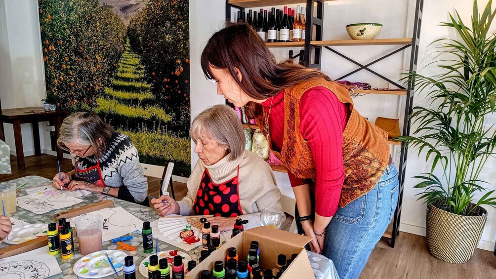 Three people painting at a table with art supplies. 3