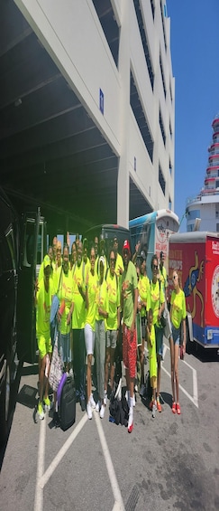 A group of people in bright yellow shirts posing in front of a parking garage. 1