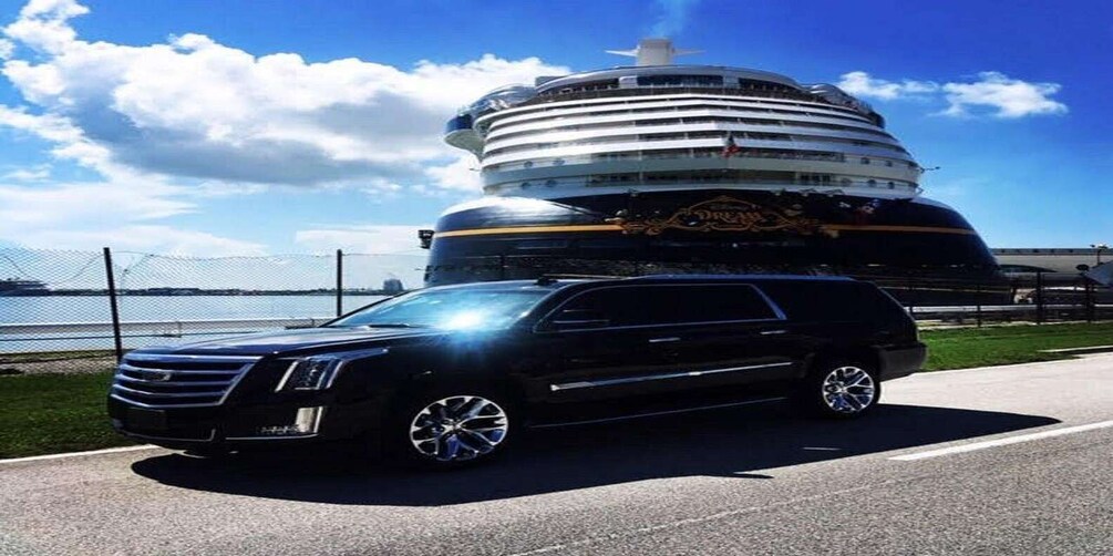 A black SUV parked on a road with a large cruise ship in the background. 4