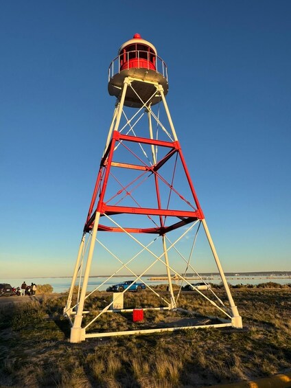 A tall red and white lighthouse structure with a clear blue sky in the background. 2