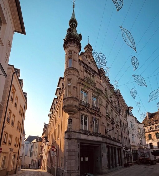 A historic building with ornate architecture, a cobblestone street, and decorative leaf patterns in the sky. 4