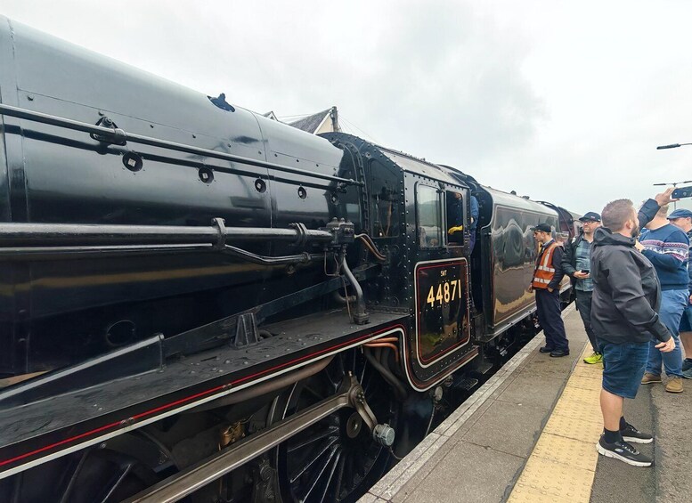 A black steam locomotive with the number 44871 parked at a station. 4