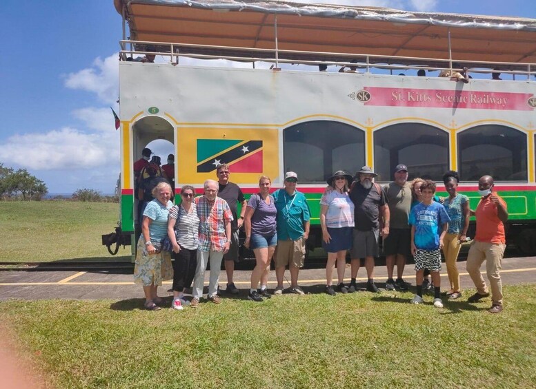 A group of people standing in front of a colorful train with a scenic railway logo. 4