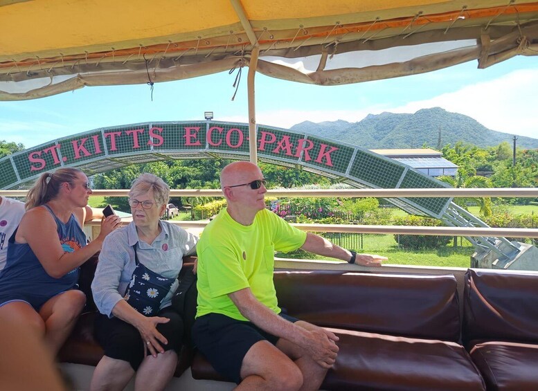 Three people sitting on a bench under a canopy at St. Kitts Eco Park with solar panels in the background. 5