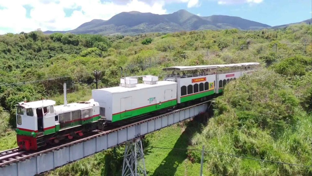 A train on a bridge with a mountainous landscape in the background. 3