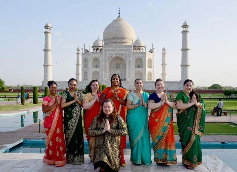 A group of people in traditional attire posing in front of the Taj Mahal. 4