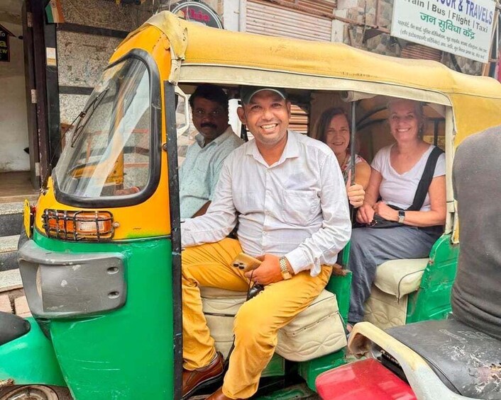 A yellow and green auto-rickshaw with passengers. 5