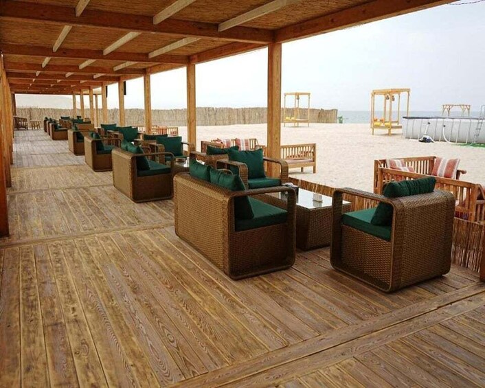 A covered outdoor seating area with wicker furniture and a wooden floor. 2