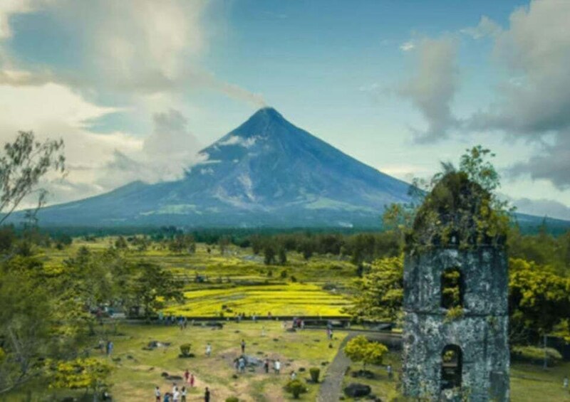 A volcano, a church tower, and a field with people. 2