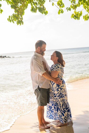 A couple standing on a beach with ocean waves in the background. 3