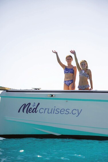 Two people in bikinis standing on a boat with 'Med cruises.cy' written on it. 5
