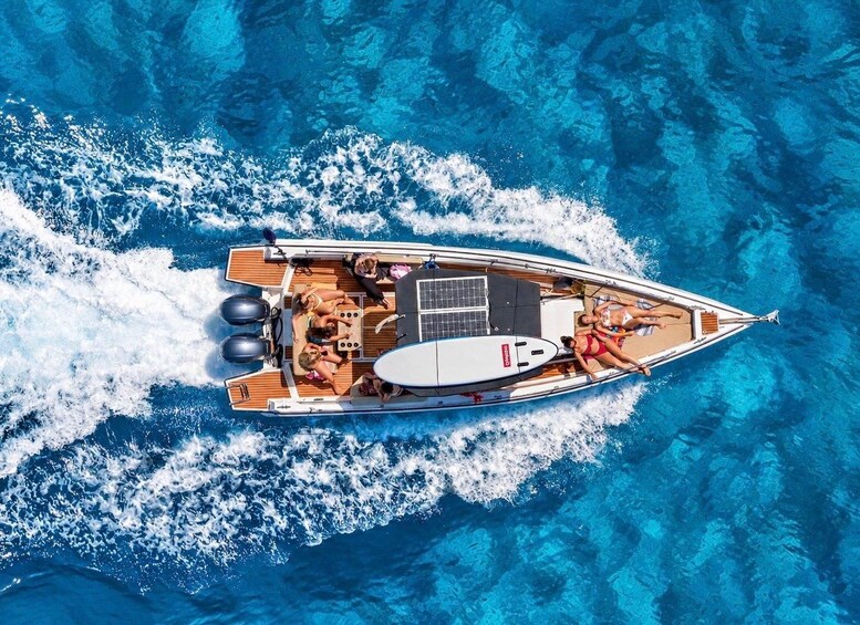 A boat with a wake, passengers, and a clear blue sea. 5