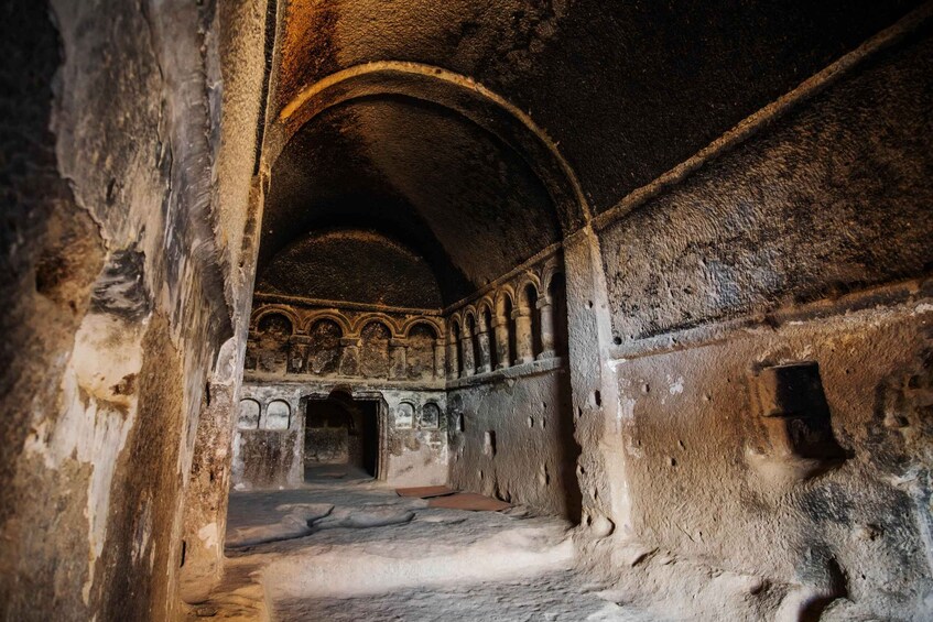An ancient, dimly lit interior with arched ceilings and stone walls. 4