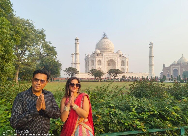Una pareja frente al Taj Mahal, con abundante vegetación y cielo despejado. 4