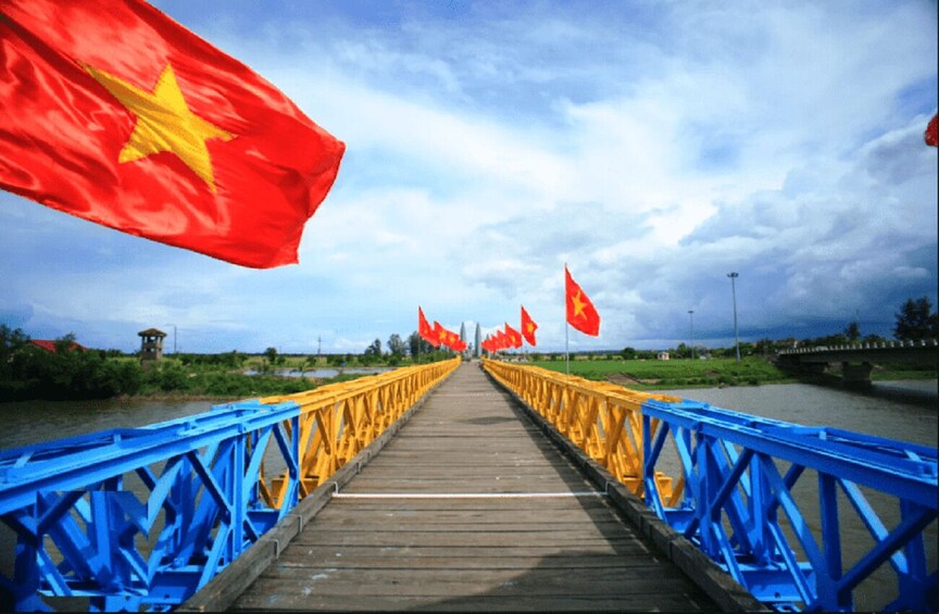 A wooden bridge with blue railings and red flags. 2
