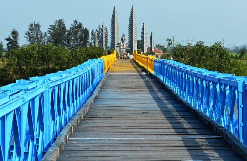 A wooden bridge with blue railings and a statue in the center. 1