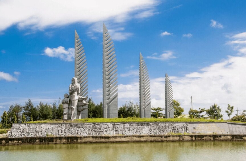 A sculpture garden with tall, leaf-like structures and a statue of a figure. 3