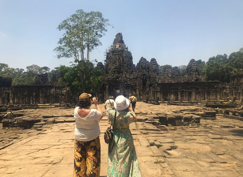 A historical site with ancient stone structures and a large tree in the foreground. 4
