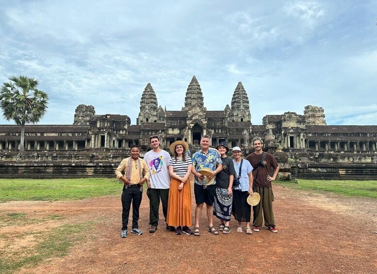 A group of people standing in front of Angkor Wat temple complex. 1