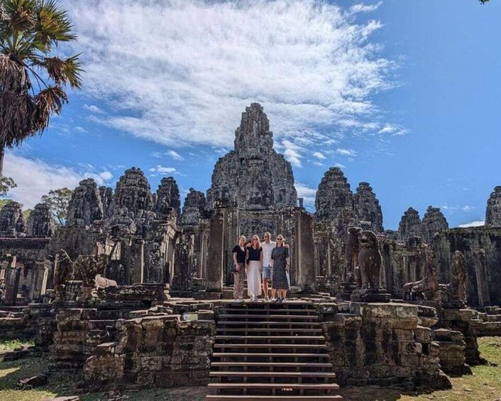 Ancient stone ruins with a central staircase and a group of people standing at the top. 3
