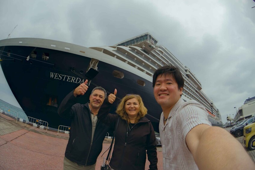 Three people taking a selfie in front of a large cruise ship named 'WESTERDA'. 2