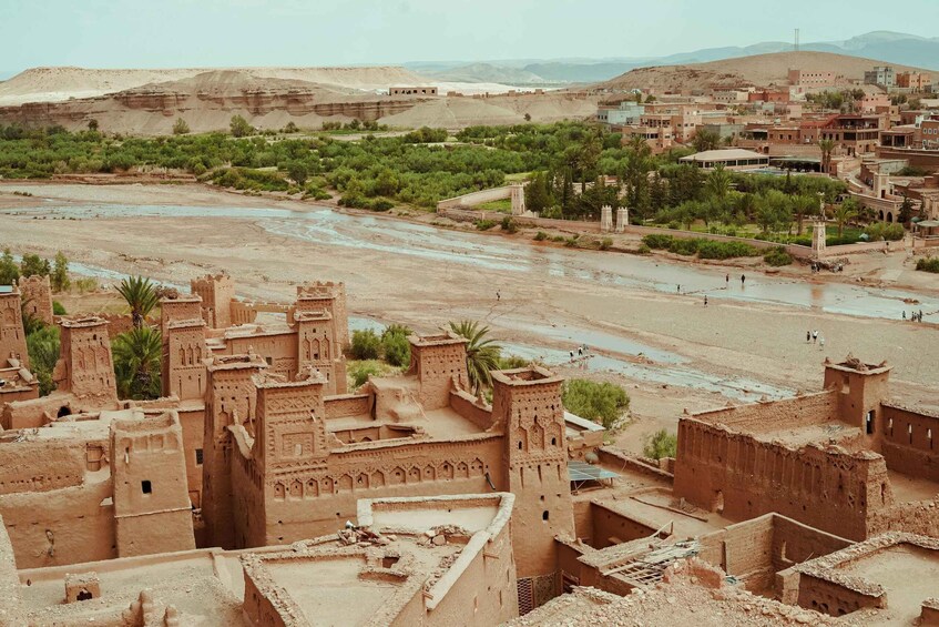 A desert landscape with a river, traditional mud-brick buildings, and sparse vegetation. 2