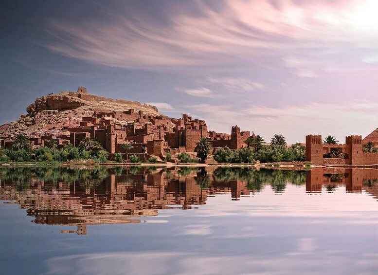 A historic fortified city with a large hill and a calm river reflecting its structures. 1