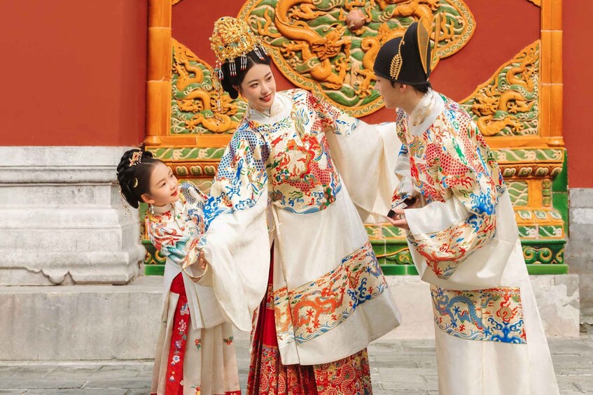 A person in traditional Chinese attire standing in front of a decorative wall with intricate designs. 2