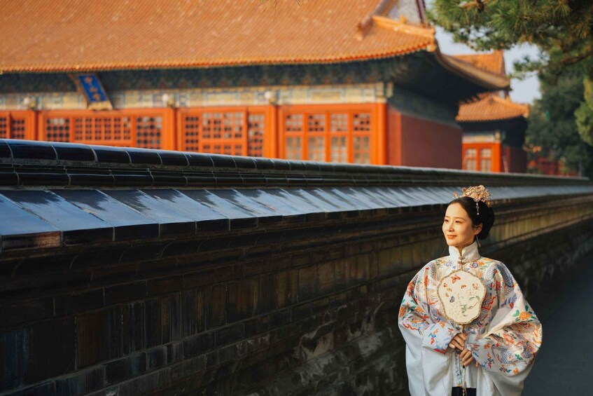 A person in traditional attire standing in front of a historical building with red doors and a tiled roof. 3