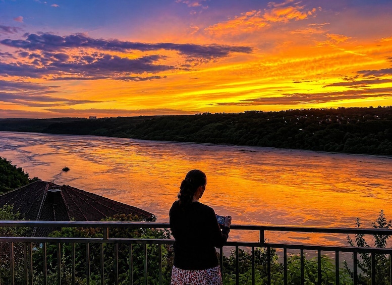 A sunset over a river with a person taking a photo. 4