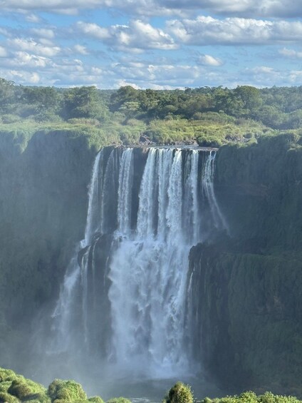 A large waterfall cascading down a steep cliff surrounded by lush greenery. 3