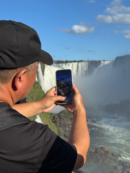 A person taking a photo of a waterfall. 4