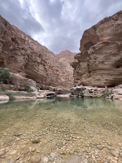 A canyon with a clear water pool surrounded by rocky terrain. 5