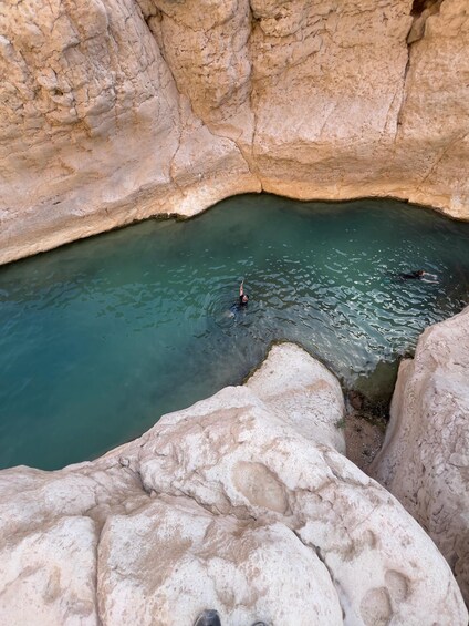 A person swimming in a natural pool surrounded by rocky cliffs. 4