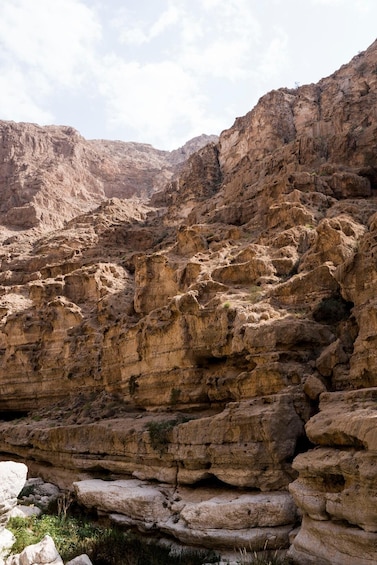 A rugged canyon landscape with layered rock formations and sparse vegetation. 5