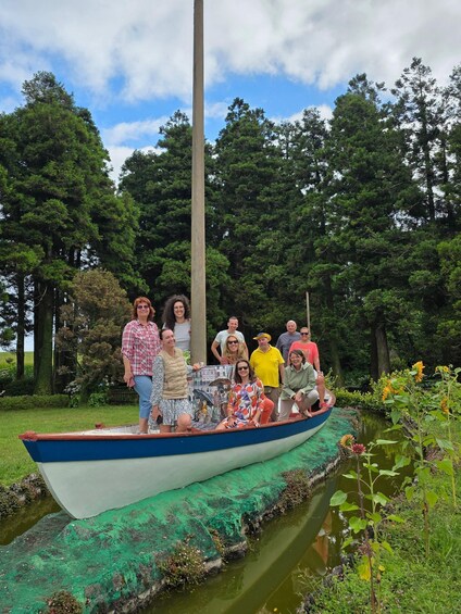 A group of people on a boat in a park with trees and a pond. 5