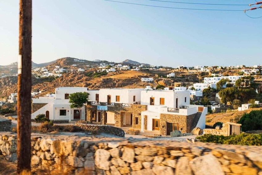A coastal village with white buildings, stone walls, and a mountainous backdrop. 5