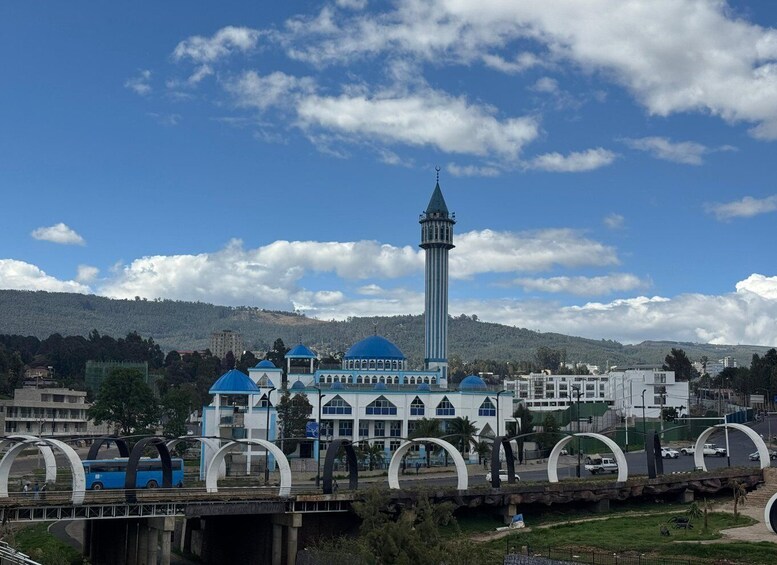 A mosque with a tall minaret, a blue-domed building, and a bridge with arches. 1