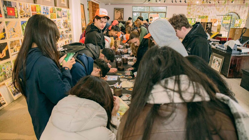 A group of people engaged in a drawing activity in a brightly lit indoor space with various artworks on the walls. 2