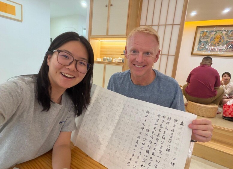 Two people holding a large sheet with Chinese characters. 3