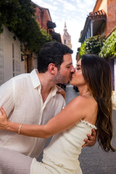 A couple dancing in a narrow street with buildings and a tower in the background. 2