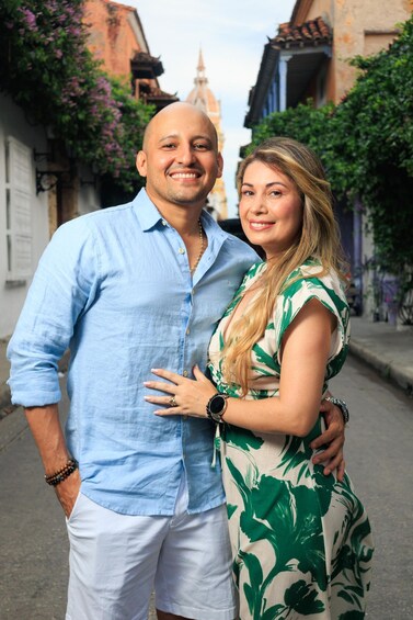 A couple standing on a narrow street with buildings and a church dome in the background. 1