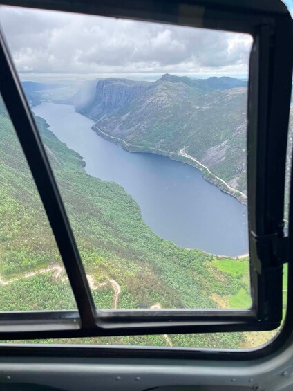 A helicopter window view of a lake surrounded by forested mountains. 4