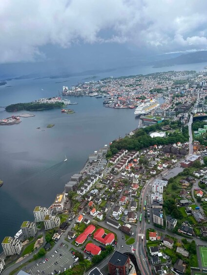 An aerial view of a coastal city with a harbor, residential areas, and a large cruise ship docked. 2
