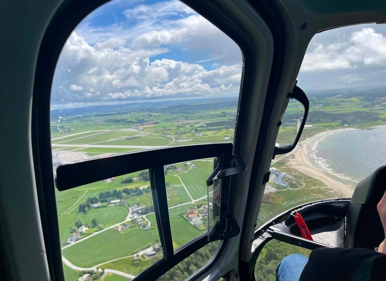 A view from an aircraft cockpit with a landscape of fields, a coastline, and scattered buildings. 3