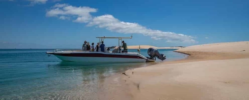 A boat on a sandy beach with clear water. 3