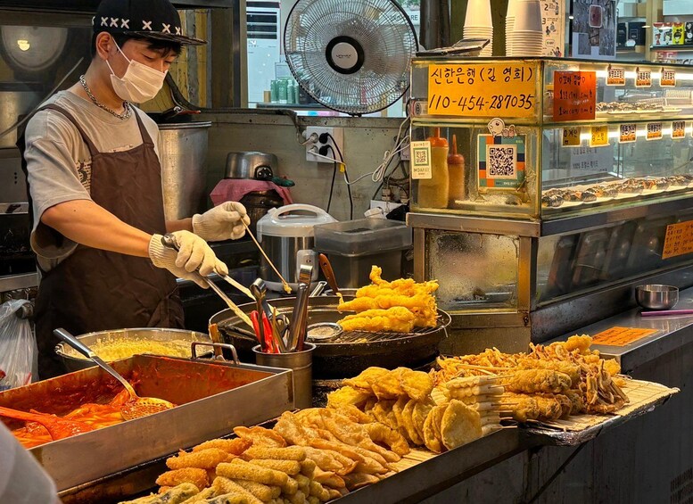A food vendor preparing and serving fried snacks. 1